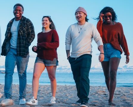 Group of 4 teenagers walking on the beach at sunset.