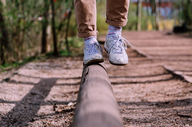 Man walking on a wooden beam along a dirt road