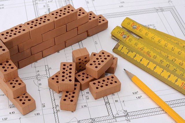Photo of brick, pencil and put to measure deposited on a house plan.