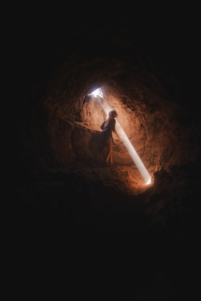 Woman inside a cave looking at an issue with a ray of light